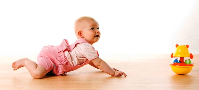 baby girl crawling towards a toy on the floor